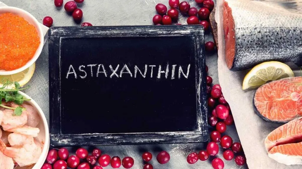 Lousa cercada de salmão, camarão e frutas vermelhas, alimentos ricos em astaxantina