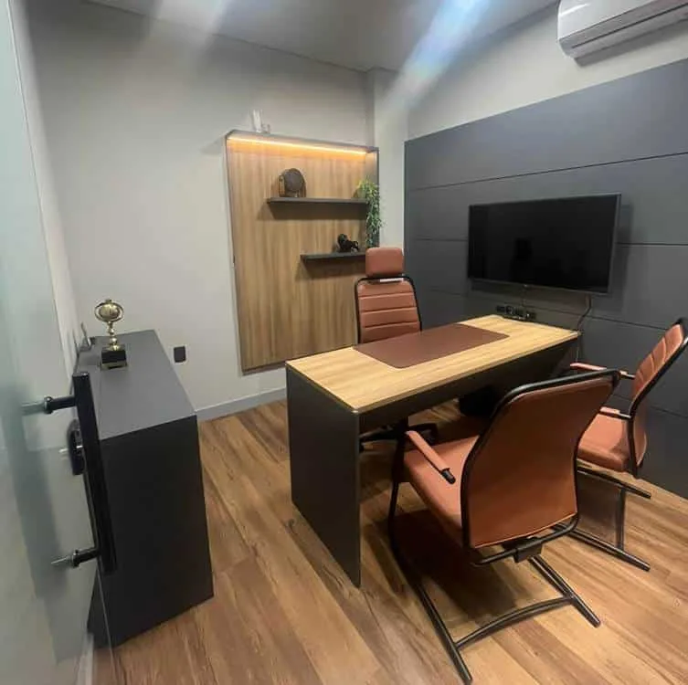 Sala de reunião mobiliada com mesa, cadeiras e televisão na parede